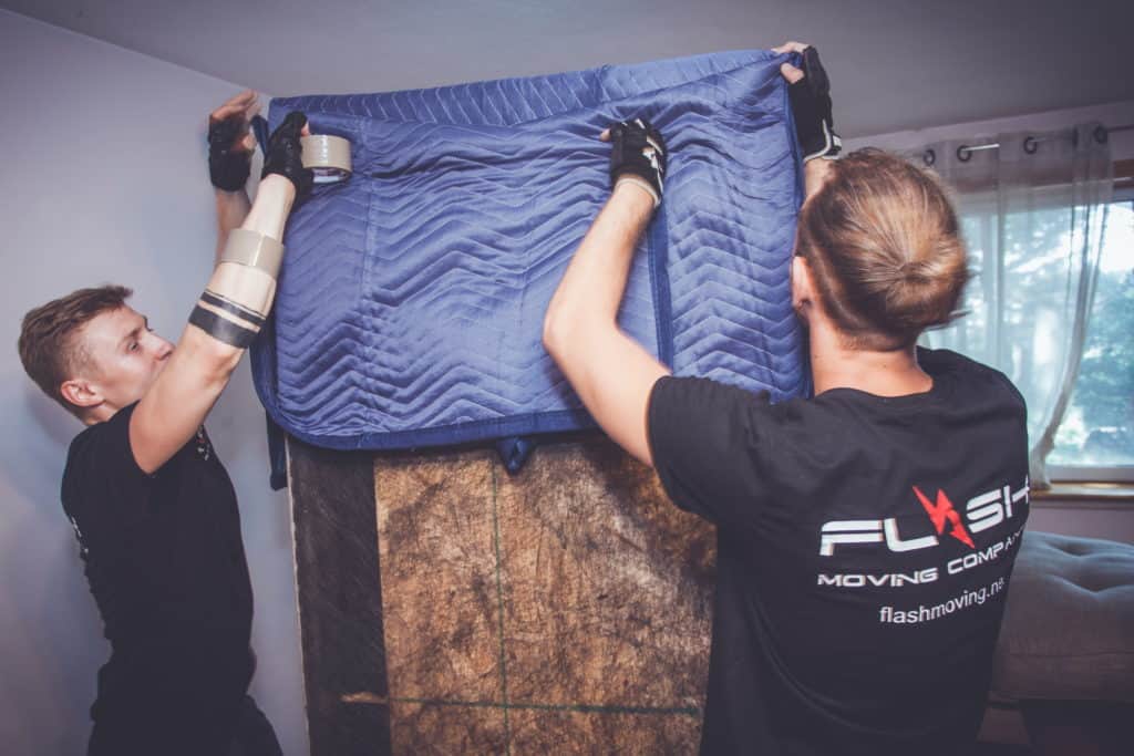 Moving Company in Waltham, two movers packing furnitur in moving pads